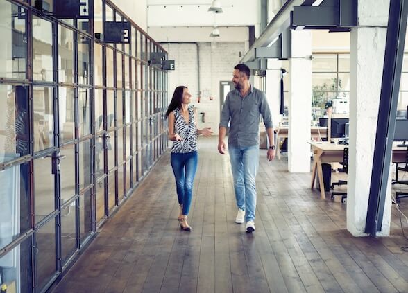 Two people walking down an office hallway